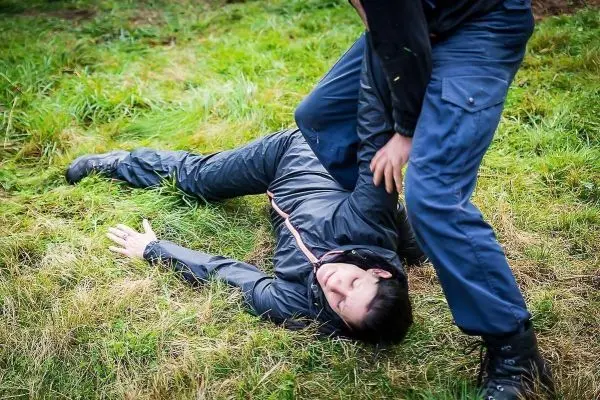 Kämpfer kontrolliert liegende Person auf Grasfläche