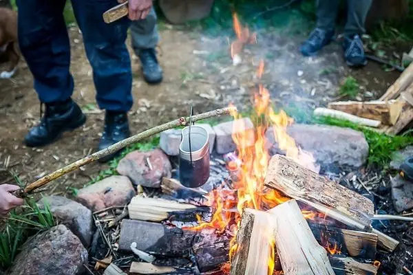 Kessel hängt über dem Feuer, Holz brennt, Flammen schlagen hoch