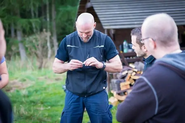 Mann hält ein Werkzeug in den Händen, umgeben von mehreren Personen
