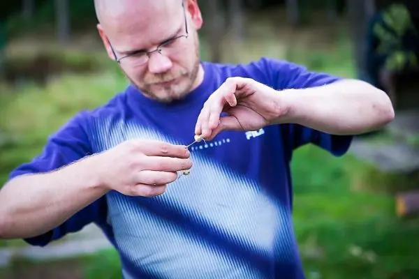 Mann hält eine kleine Schnur und bindet einen Knoten