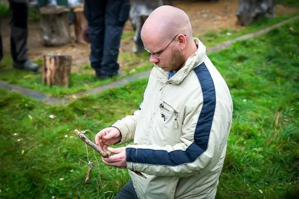 Mann hält einen Stock mit einer Schnur in der Hand und konzentriert sich darauf