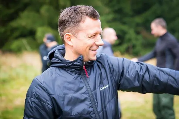 Mann in Jacke interagiert mit anderen Personen im Hintergrund