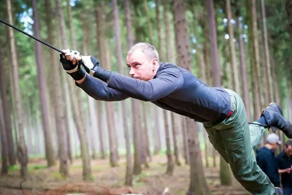 Mann überquert selbstgebaute Seilbrücke im Wald