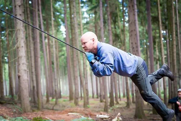 Mann überquert selbstgebaute Seilbrücke zwischen Bäumen im Wald