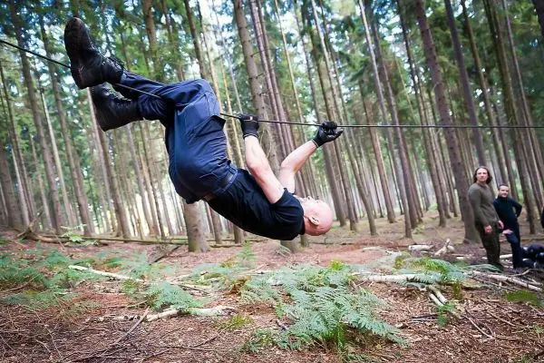 Mann überquert selbstgebaute Seilbrücke zwischen Bäumen im Wald