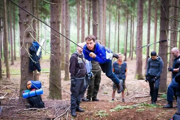 Mann überquert selbstgebaute Seilbrücke zwischen Bäumen im Wald