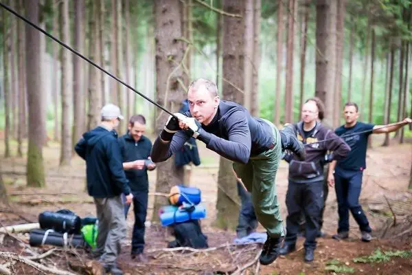 Mann überquert selbstgebaute Seilbrücke zwischen Bäumen im Wald