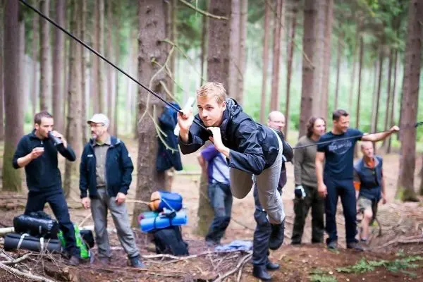 Mann überquert selbstgebaute Seilbrücke zwischen Bäumen im Wald