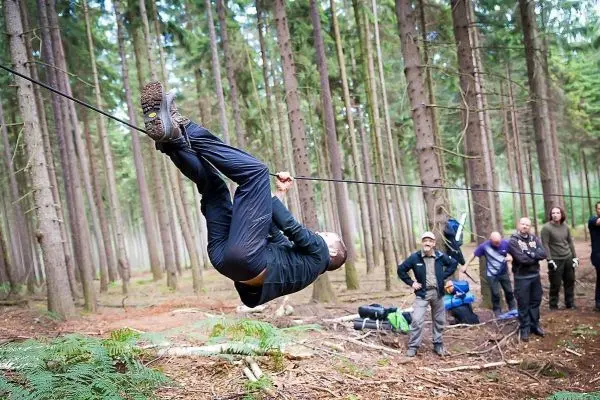 Mann überquert selbstgebaute Seilbrücke zwischen Bäumen im Wald