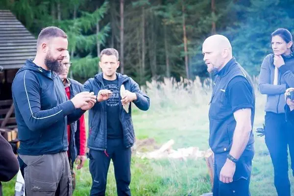 Mann zeigt Zunder während andere Teilnehmer aufmerksam zuschauen