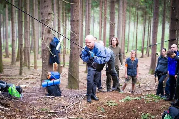Mann zieht an einem Seil während einer Seilquerung im Wald