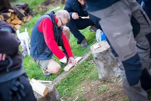 Messer bearbeitet Holzstück auf einem Baumstumpf im Freien