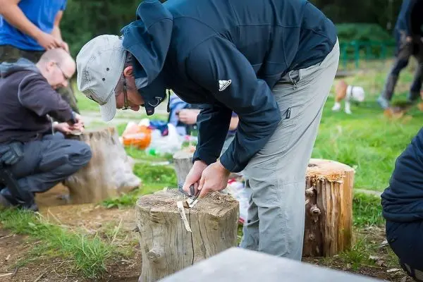 Messer schnitzt Holzstück auf einem Baumstumpf im Freien