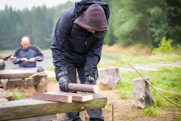 Person bearbeitet Holzstück auf einer Bank beim Überlebenstraining