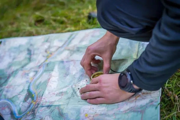Person hält einen Kompass über eine Landkarte