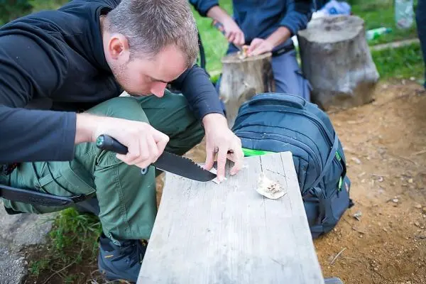 Person schnitzt mit einem Messer auf einem Holzbrett