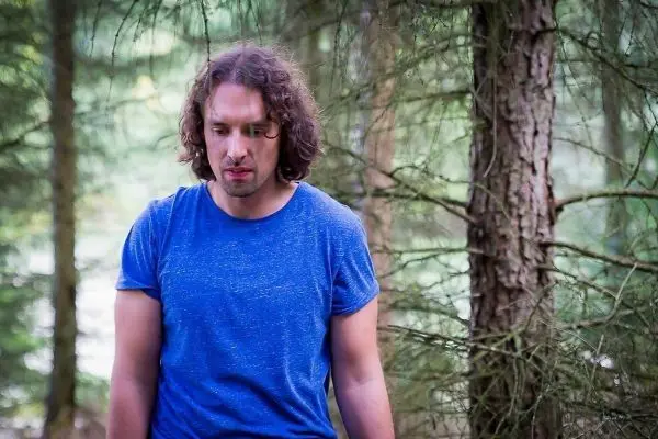 Person steht zwischen baeumen im wald