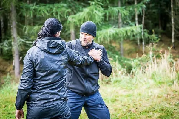 Person übt Selbstverteidigungstechniken mit einer anderen Person im Wald