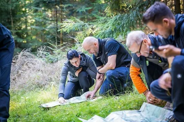 Personen betrachten eine Karte auf dem Boden im Wald
