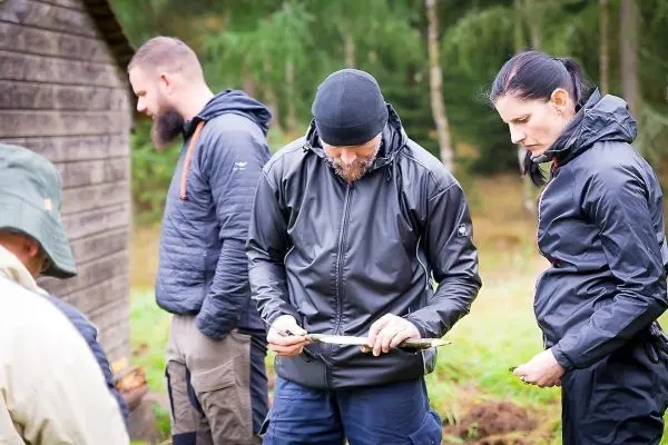 Teilnehmer bearbeitet einen Stock mit einem Messer im Wald