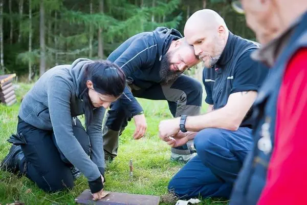 Zunder wird auf einer Holzplatte bearbeitet, während mehrere Personen beobachten