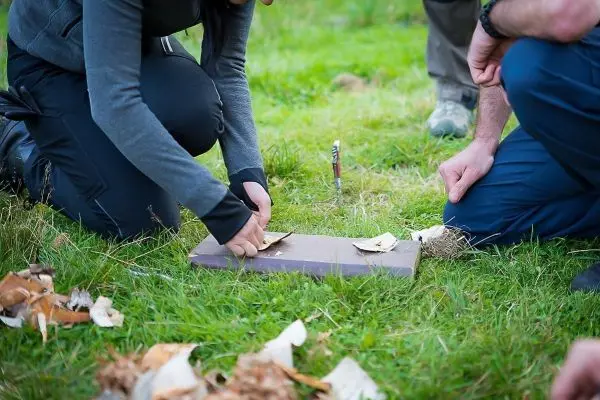 Zunder wird auf einer Holzplatte vorbereitet, während zwei Personen beobachten