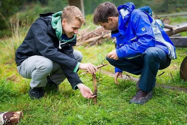 Zwei Personen bauen eine kleine Konstruktion aus Ästen