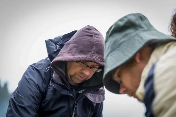 Zwei Personen beugen sich über einen Tisch, konzentriert bei einer Tätigkeit