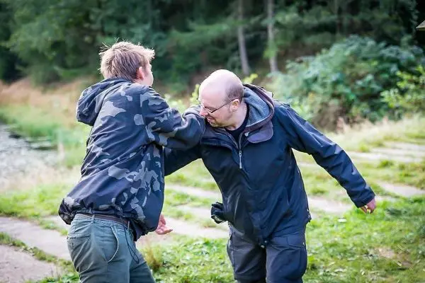 Zwei Personen in einer körperlichen Auseinandersetzung am Ufer eines Gewässers