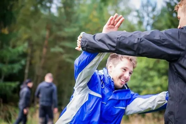 Zwei Personen in Outdoor-Bekleidung führen eine Übung im Wald durch