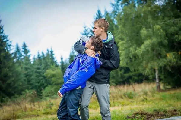 Zwei Personen in Outdoor-Bekleidung üben eine Selbstverteidigungstechnik im Freien