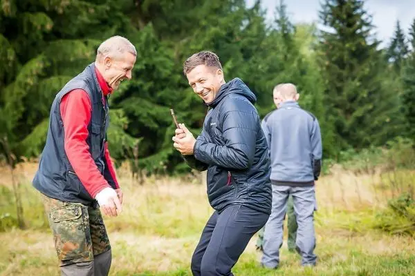 Zwei Personen lachen und halten ein Messer in einer Waldlichtung