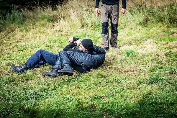 Zwei Personen liegen auf dem Gras, eine Person hält die andere fest