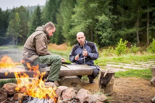 Zwei Personen sitzen an einer Feuerstelle und unterhalten sich