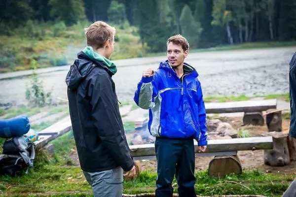 Zwei Personen stehen am Ufer eines Gewässers und unterhalten sich