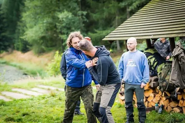 Zwei Personen üben eine körperliche Technik, während zwei weitere Zuschauer beobachten