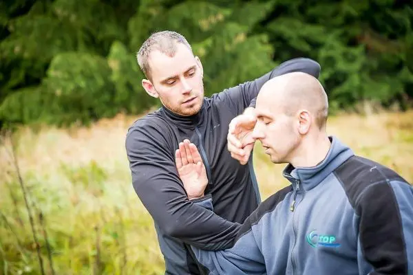 Zwei Personen üben eine Selbstverteidigungstechnik im Freien