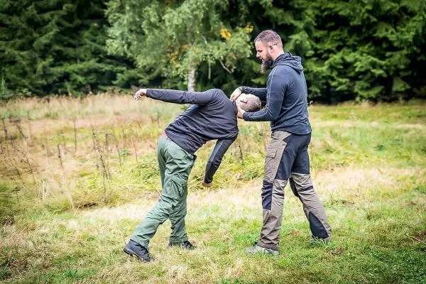 Zwei Personen üben eine Selbstverteidigungstechnik im Freien