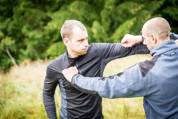 Zwei Personen üben eine Selbstverteidigungstechnik im Freien