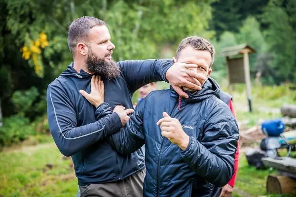 Zwei Personen üben eine Selbstverteidigungstechnik im Freien aus