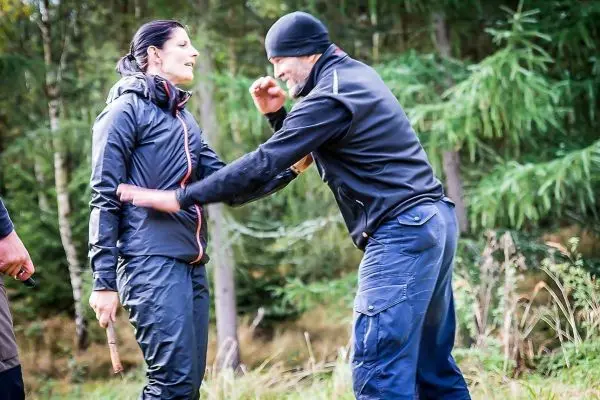Zwei Personen üben eine Selbstverteidigungstechnik im Wald