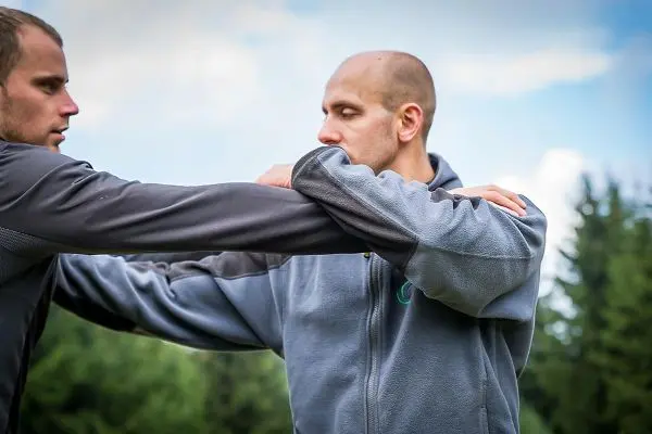 Zwei Personen üben eine Technik mit verschränkten Armen im Freien