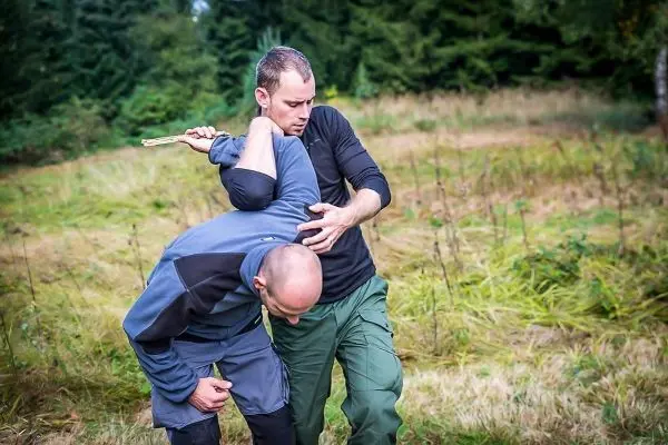 Zwei Personen üben eine Technik zur Kontrolle des Gegners im Freien