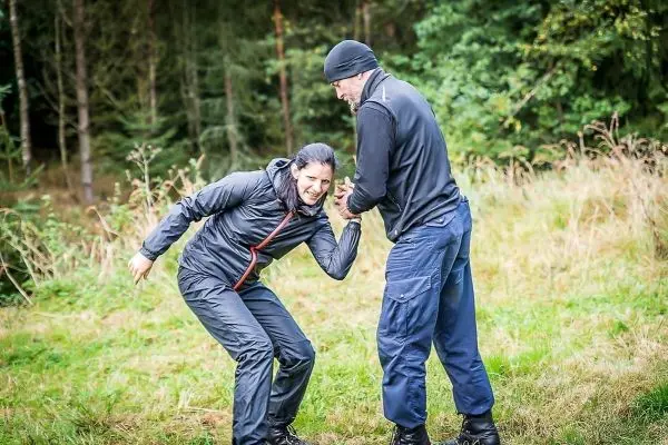 Zwei Personen üben eine Technik zur Selbstverteidigung im Freien