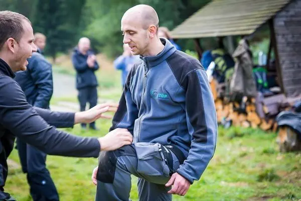 Zwei Personen üben eine Technik zur Unterstützung bei einer Verletzung im Freien