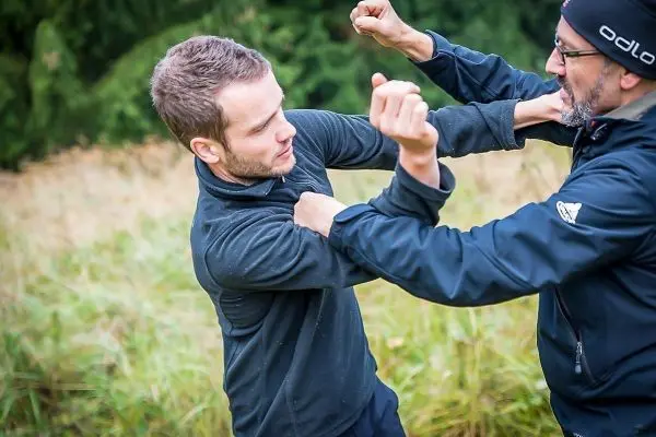 Zwei Personen üben einen Nahkampf mit Schlägen und Abwehrbewegungen im Freien