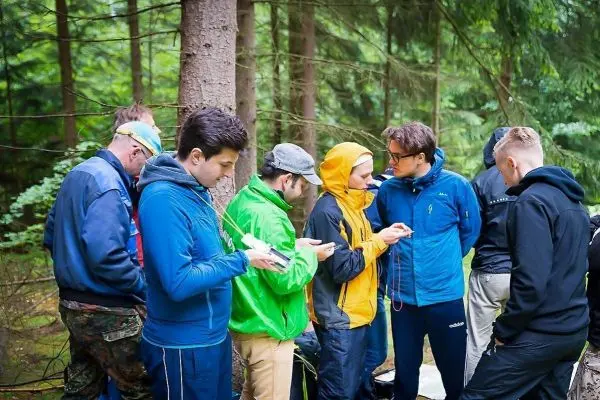 Gruppe von Personen in Outdoor-Bekleidung nutzt mobile Geräte im Wald