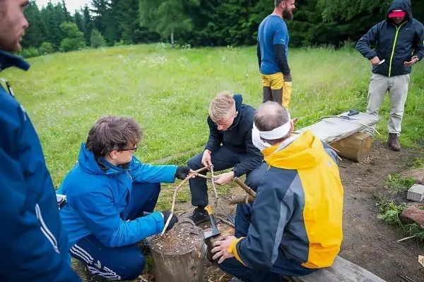 Gruppierung arbeitet an einer selbstgebauten Konstruktion aus Holzstücken auf Baumstämmen