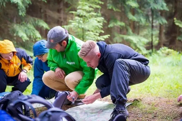 Gruppierung von Personen betrachtet eine Karte auf dem Boden im Wald