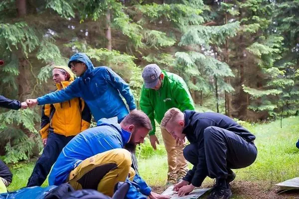 Gruppierung von Personen betrachtet Karte auf dem Boden im Wald